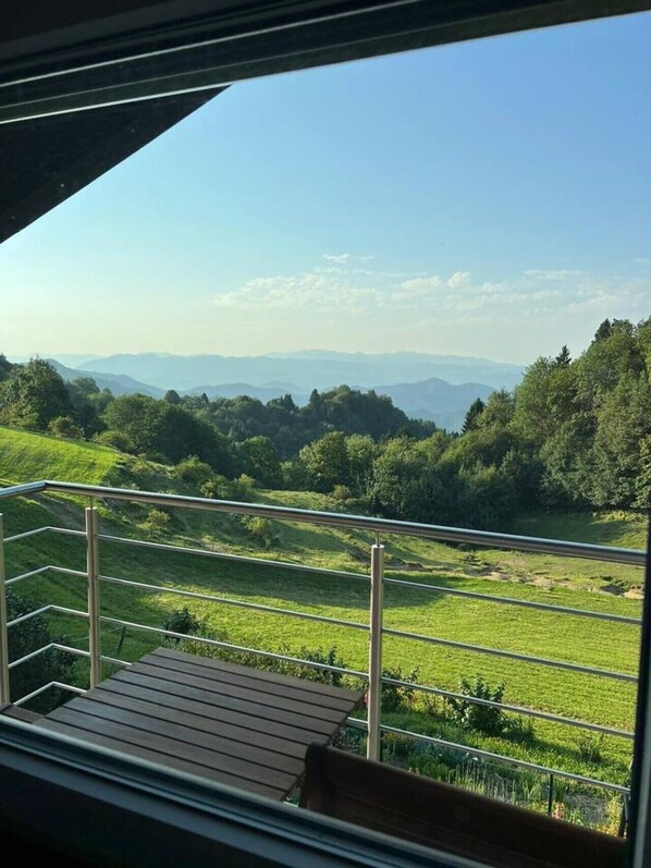 A balcony with a view of a green landscape and distant mountains. - Charming Alpine Apartment with Sauna (Kobarid)