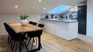 A modern kitchen with a central island, recessed ceiling lights, and a skylight. - Charming Alpine Apartment with Sauna (Kobarid)
