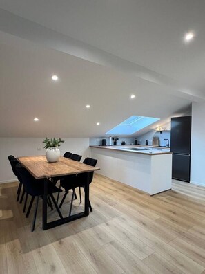 A modern kitchen with a central island, recessed ceiling lights, and a skylight. - Charming Alpine Apartment with Sauna (Kobarid)