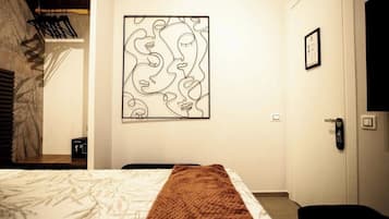 A hotel room with a bed, a wall-mounted artwork, a door, and a bench.