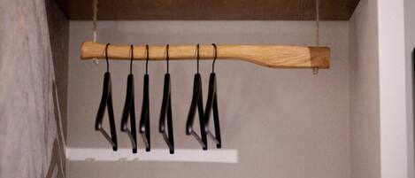 A wooden rack with black hangers against a wall.