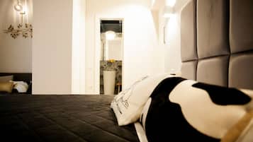 Une chambre à coucher comprenant un lit, une table de chevet, un luminaire fixé au mur et une porte donnant accès à une salle de bain.