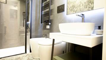 A modern bathroom with a glass shower enclosure, a white sink, and a towel rack.