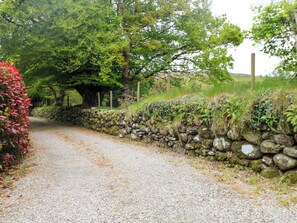 A gravel path flanked by a stone wall and lush greenery.