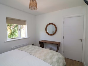 A bedroom with a bed, a window, a mirror, a door, and a radiator. - THE MEWS @ DERRYBAWN, pet friendly in Laragh, County Wicklow (Glendalough)