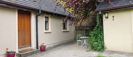 A house with a door, windows, a small patio, and a garden area.