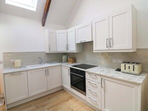 A kitchen with white cabinets, a countertop, a sink, a stove, and a toaster.