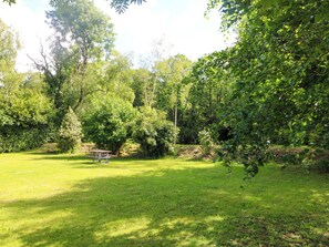 A grassy outdoor area with a picnic table and dense trees. - THE MEWS @ DERRYBAWN, pet friendly in Laragh, County Wicklow (Glendalough)