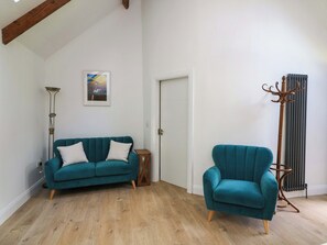 A room with a teal sofa, a matching armchair, a floor lamp, and a radiator. - THE MEWS @ DERRYBAWN, pet friendly in Laragh, County Wicklow (Glendalough)