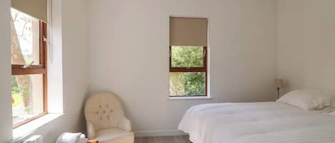 A bedroom with a bed, a chair, a window, and a radiator.