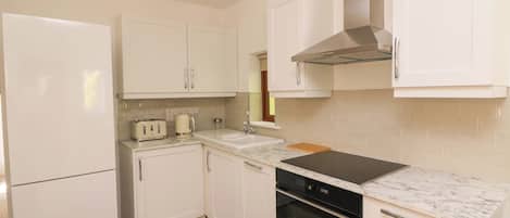 A kitchen with white cabinets, a built-in oven, a stove, and a refrigerator.