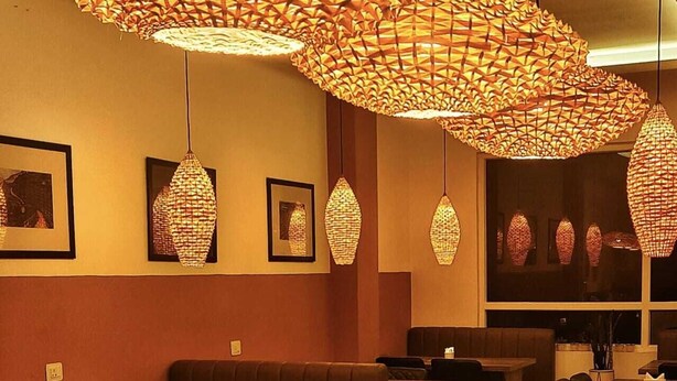 L’intérieur d’un restaurant est agrémenté de plusieurs suspensions, de sièges rembourrés et d’œuvres d’art encadrées qui ornent les murs.
