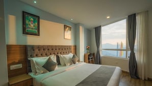 Une chambre d’hôtel avec un grand lit, une tête de lit en bois, un bureau et une vue sur les montagnes par la fenêtre.
