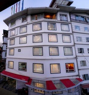 A multi-story building with numerous windows, balconies, and a red awning. - Mandarava Hotel (Gangtok)