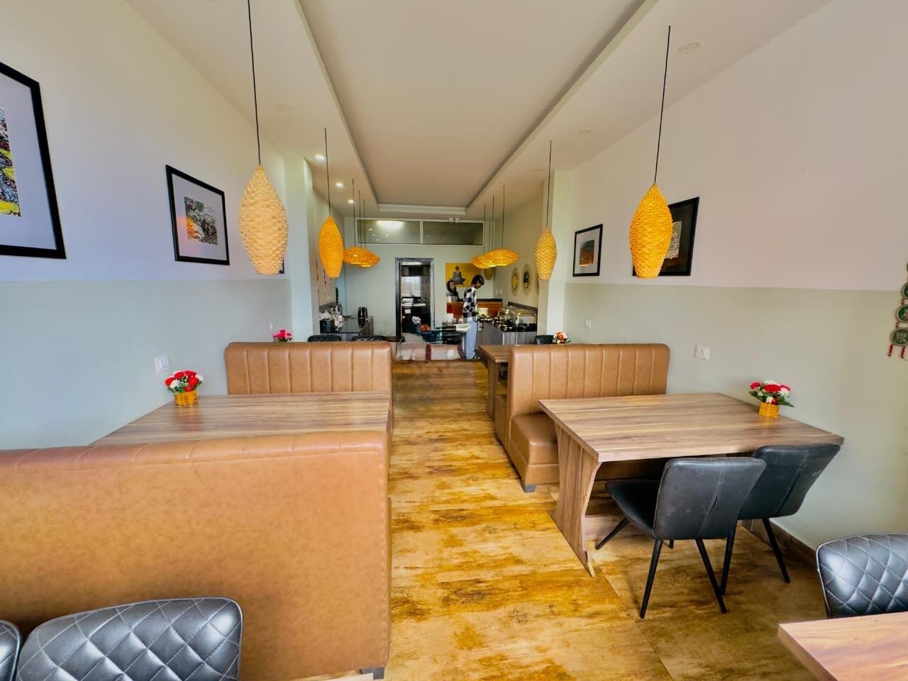 A modern dining area with high tables and cushioned seating, pendant lighting, and artwork on the walls.