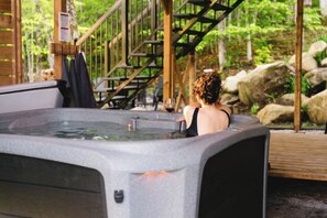 A hot tub in a natural setting with wooden structures and stairs. - Java with Private Spa, Lake & Kayak (St-Raymond)