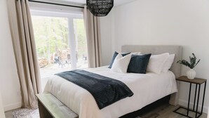 Een slaapkamer met een bed, een bankje, een nachtkastje en uitzicht op de omgeving.
