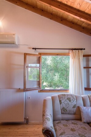 Una habitación con techo de madera, un radiador, un ventanal con cortina y un sofá estampado.