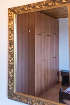 Una habitación con armario, cama y una mesita.