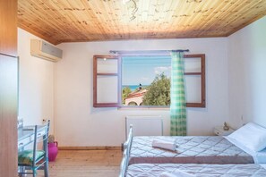 Ein Schlafzimmer mit Holzboden, einem Fenster mit Ausblick, einem Bett, einem Sessel und einer Heizung.