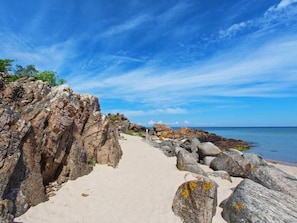 A rocky coastal path leading to the sea with clear skies. - The Apple Garden (Allinge)