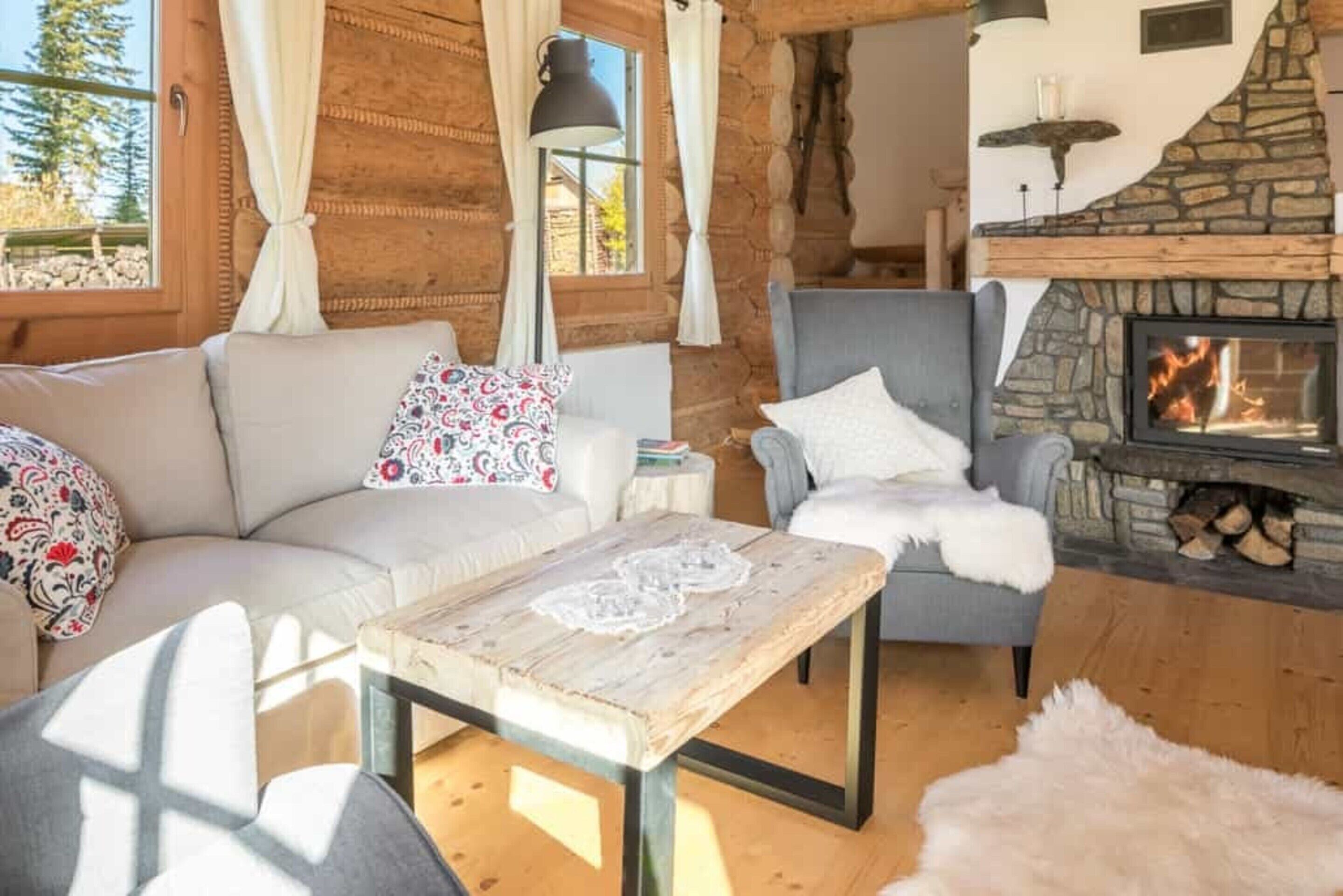 Ein gemütliches Wohnzimmer mit Kamin aus Stein, einer Couch, einem Sessel und einem Couchtisch.