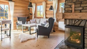 A cozy log cabin interior with a fireplace, wooden walls, a sofa, and a dining table. - Holiday Villa With Mountain Views, Koscielisko (Koscielisko)