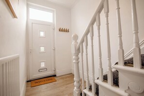 A staircase with white balusters, a white door with a window, and a doormat with 'WELCOME' written on it. - Group Haven 5 Bed 2 Bath | Hot Tub | Pool Table (Sheffield)