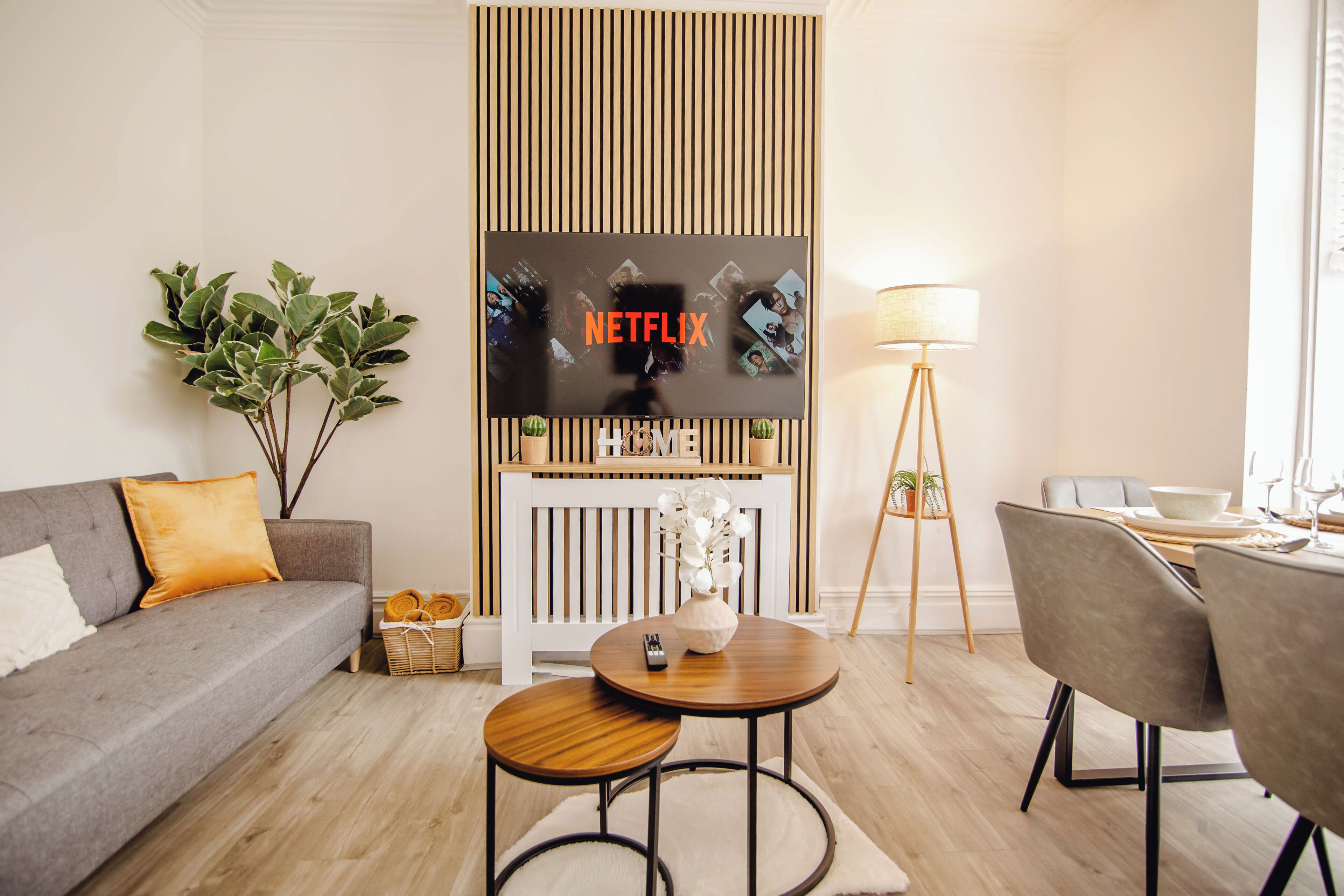 Un saló modern amb un sofà, una taula de centre, una làmpada i un televisor fixat a la paret.