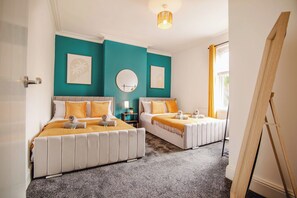 A hotel room with two beds, teal walls, a round mirror, and a wooden easel. - Group Haven 5 Bed 2 Bath | Hot Tub | Pool Table (Sheffield)