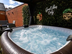 An inflatable hot tub with a brick wall and greenery in the background, and neon signs with motivational phrases. - Group Haven 5 Bed 2 Bath | Hot Tub | Pool Table (Sheffield)