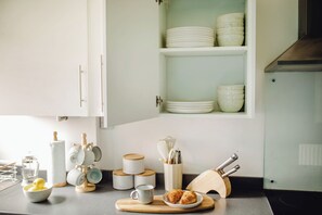 A kitchen with white cabinets, a countertop with tea and sugar containers, a cutting board with croissants, and a knife block. - Group Haven 5 Bed 2 Bath | Hot Tub | Pool Table (Sheffield)