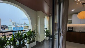Ein Hotelbalkon mit Blumentöpfen, Blick auf die Stadt und eine moderne Küchenzeile.