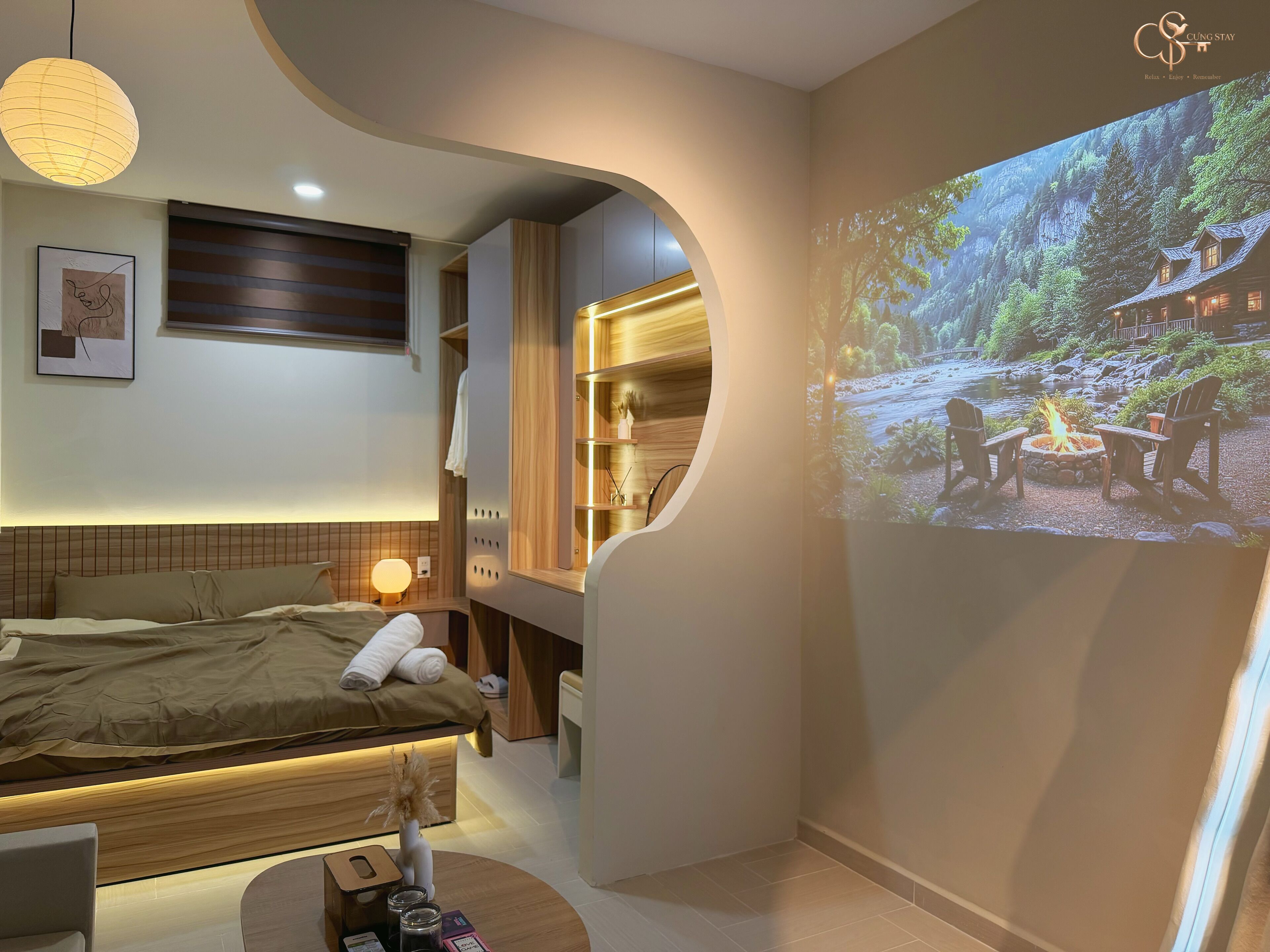 Un dormitorio moderno con cama, mesita de noche y un proyector de pared que muestra una vista panorámica al aire libre.
