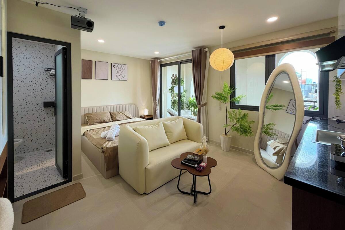 A modern living room with a sofa, a coffee table, a bed, and a large mirror.