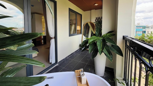 Ein Balkon mit einer weißen Badewanne, Blumentöpfen und Blick auf Gebäude.