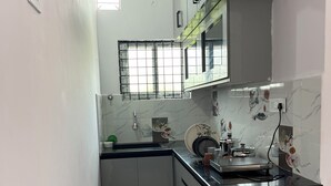 A kitchen with a marble countertop, a sink, and a window with a grid pattern.