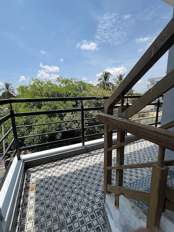 A metal staircase with a metal railing leading to a tiled floor, surrounded by greenery and buildings.. Sapthasiri Holiday Homes-Chandanavana (Non- AC)
