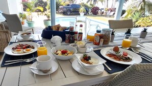 A breakfast table with plates of food, drinks, and condiments. - The Lazy Shark (Freeland Park)