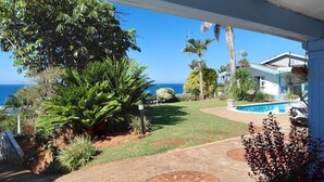 A covered outdoor area with a pool, palm trees, and a view of the ocean. - The Lazy Shark (Freeland Park)