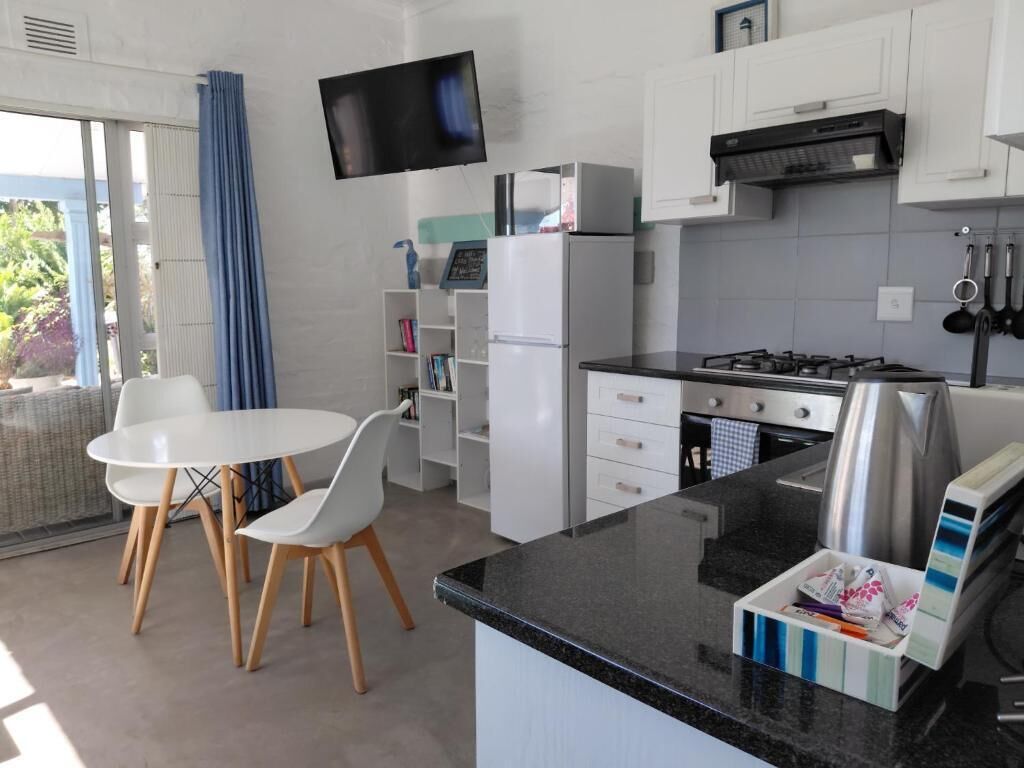 A modern kitchen with a dining area, white cabinets, a flat-screen TV, and a gas stove.