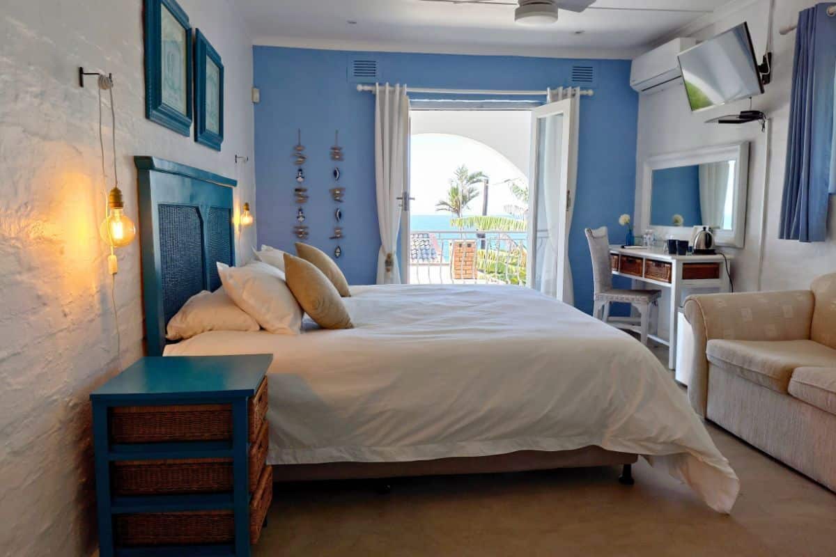 A bedroom with a bed, bedside table, and a view of the outside.