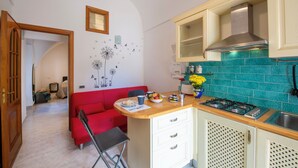 Une cuisine compacte avec un canapé rouge, une petite table à manger et une cuisinière à gaz.