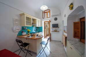 Une cuisine compacte dotée d’un îlot central, d’un coin repas avec des chaises et d’un petit espace bar.