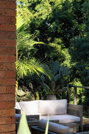 An outdoor seating area with a brick wall, a cactus plant, and dense foliage in the background. - “Surfer's Abode” – minutes to the Beach (Avoca Beach)