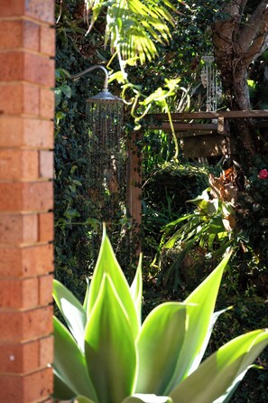 A garden with a brick wall, a hanging light fixture, and various plants. - “Surfer's Abode” – minutes to the Beach (Avoca Beach)