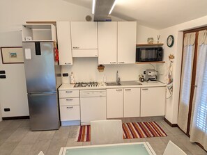 A modern kitchen with white cabinets, a stainless steel refrigerator, a microwave, and a gas stove. - Villa Lucrezia – 4 guests in Bardolino, Lake Garda – Pool, Garden, Parking, Pets Welcome (Bardolino)