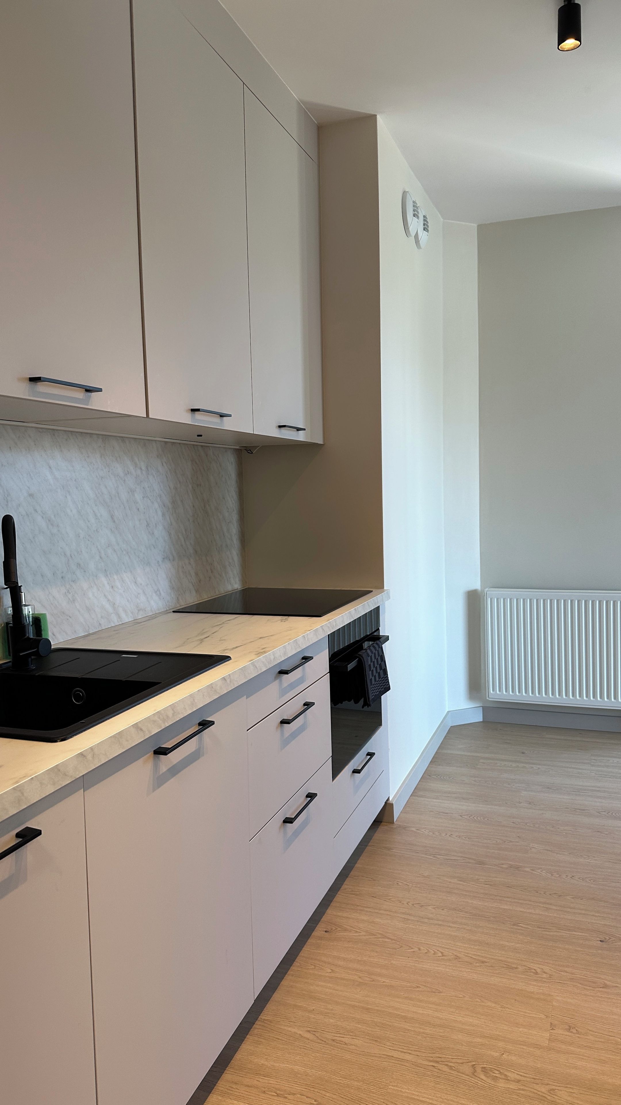 Una cocina moderna con gabinetes blancos, encimera negra y horno integrado.