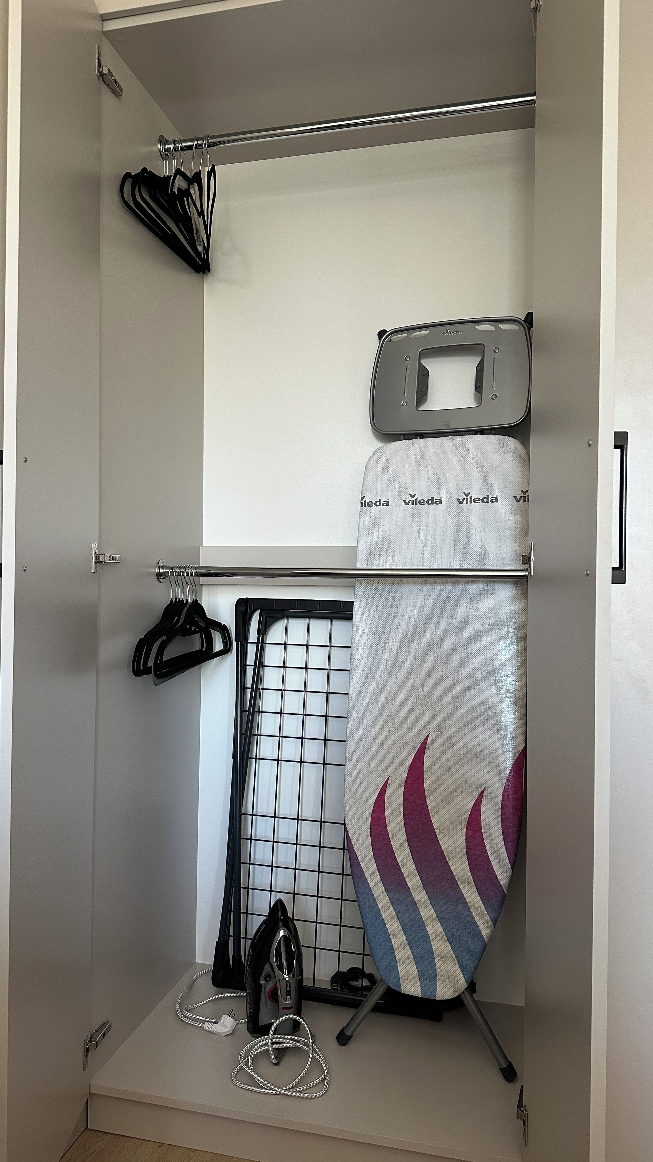 A closet with hanging space, a drying rack, and storage boxes.