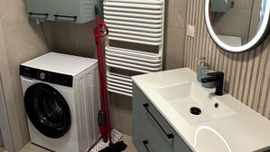 A bathroom with a washing machine, a mirror, and a towel rack.